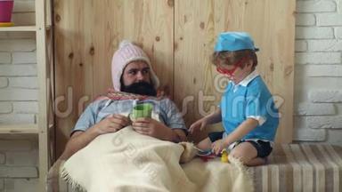 医生游戏的概念。 医生带着听诊器的眼镜孩子在家检查父亲。 医生制服男